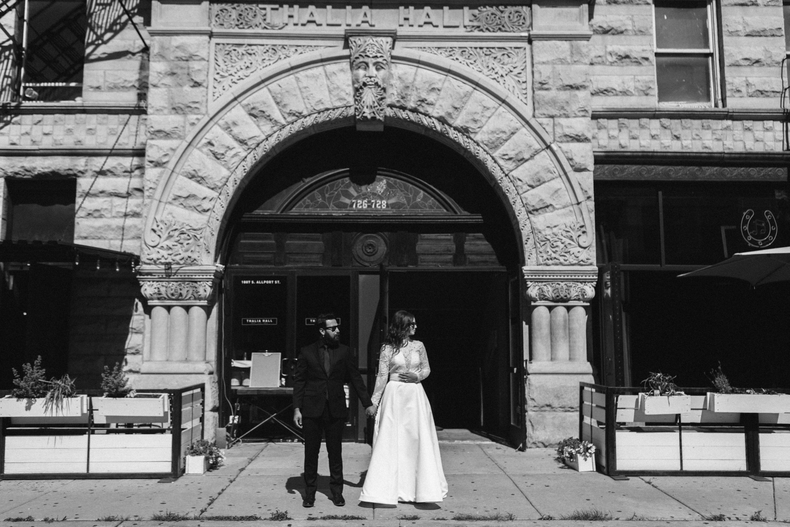 Bride and groom in their wedding attire looking across the street outside Thalia Hall in Chicago.